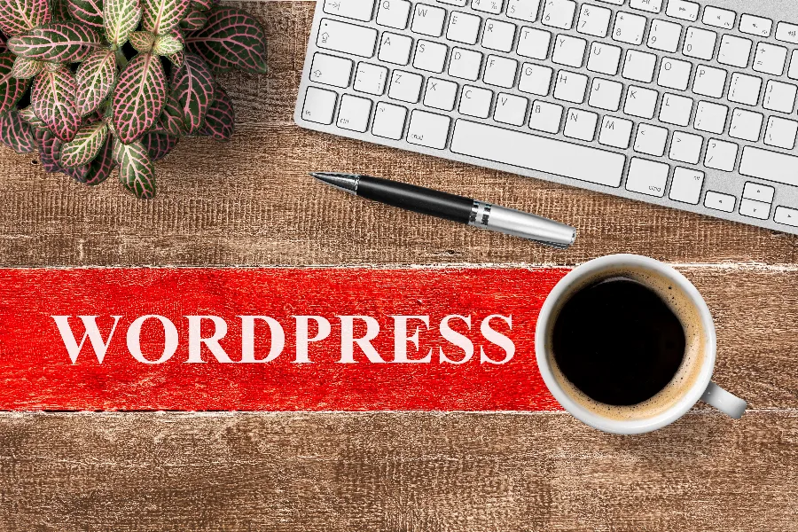 A desk with a cup of coffee and a WordPress sign